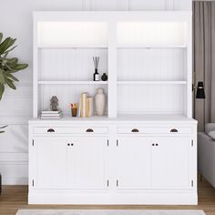 a white bookcase with books and vases on top of it in a living room