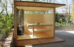 an outdoor sauna in the middle of a yard with trees and bushes behind it