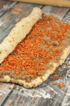 an uncooked pizza on a wooden table next to a rolling pin and some spices