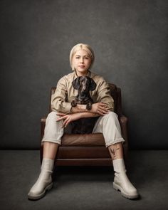 a woman sitting on top of a brown chair next to a small dog in her lap