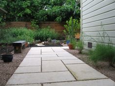 an outdoor patio area with stone walkway and potted plants on the side of the house