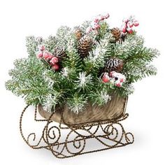 a small metal sleigh with flowers and pine cones in it on a white background