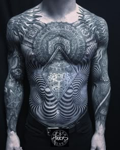 a man with tattoos on his chest and chest is standing in front of a black background