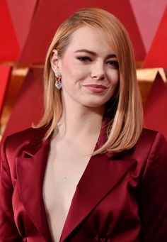 a woman in a red suit posing for the camera at an oscars event with her eyes closed