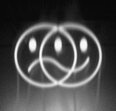 two circles with faces drawn on them in front of a black and white background that appears to be blurry