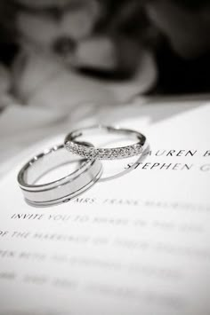 two wedding rings sitting on top of an open book with the word written in it