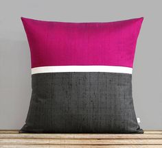 a red and grey pillow sitting on top of a wooden table