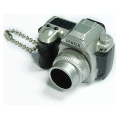 a silver digital camera sitting on top of a white table next to a ball chain