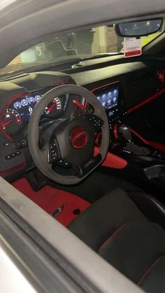 the interior of a sports car with red and black leather trims, steering wheel and dash lights