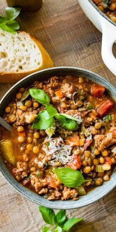 a bowl filled with soup next to some bread on a wooden table and another bowl in the background