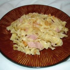 a brown plate topped with pasta and ham