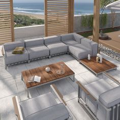 an outdoor living area with couches, tables and umbrellas on the deck overlooking the ocean