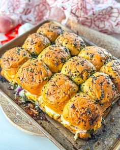 a tray filled with rolls covered in cheese and toppings on top of a table