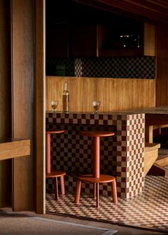 a table and chairs in a room with checkered flooring on the wall behind them