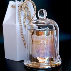 a clear glass jar with a gold lid next to a white paper bag on a black surface