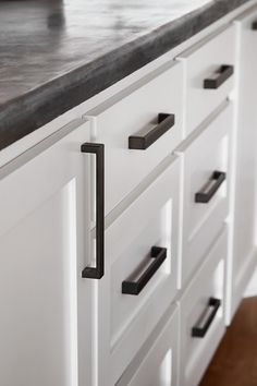 a kitchen counter top with black handles and drawers in the center, along with white cabinets