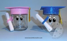 two glass jars with faces and graduation caps on them, one has a marker in its mouth