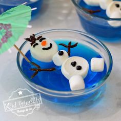 two marshmallows in the shape of snowmen sitting on top of blue liquid