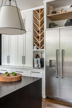 a kitchen with white cabinets and stainless steel refrigerator freezer next to wooden cutting board