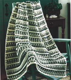 a crocheted blanket sitting on top of a wooden chair next to a table