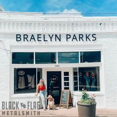 a woman standing in front of a store with her dog