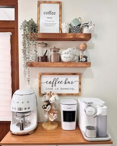 there are coffee machines and cups on the counter in this small room with wood shelves