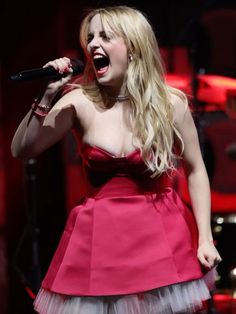 a woman in a red dress singing into a microphone