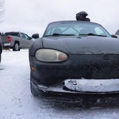 a car that is sitting in the snow with it's hood up and headlight on