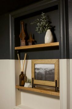 two shelves with pictures and vases on them in a room that is painted black and white