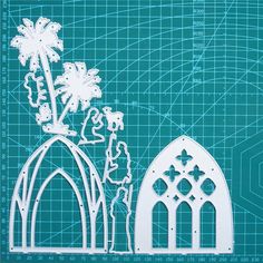 a paper cutout of a church and palm tree on a blueprinted background