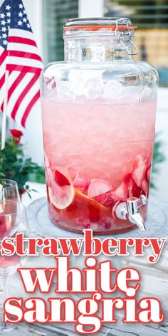 strawberry white sangria in a large glass jar with ice and garnishes