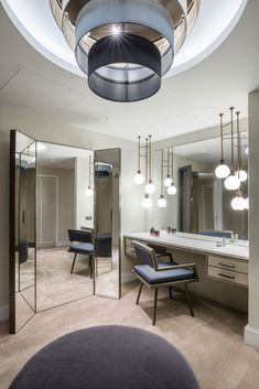 a room with mirrors, chairs and lights on the ceiling is lit by round lights