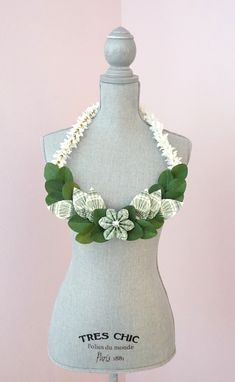 a mannequin wearing a green and white flower necklace on it's neck