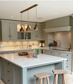 a kitchen island with two stools in front of it and lights hanging from the ceiling