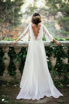 the back of a woman's dress, with her arms outstretched in front of an ivy covered wall