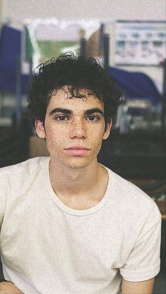 a young man with freckles on his face sitting in front of a computer desk