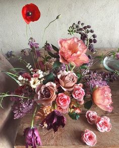 a vase filled with lots of flowers sitting on top of a wooden table next to a wall