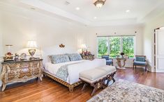 a bedroom with white walls and wood flooring has a large bed in the center