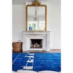 a living room with a blue rug and a gold mirror on the fireplace mantel