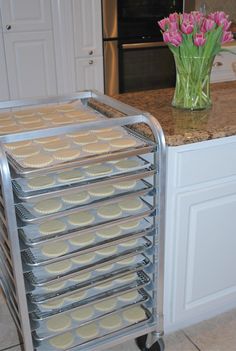 a stack of cupcakes sitting on top of a metal rack next to a vase with flowers