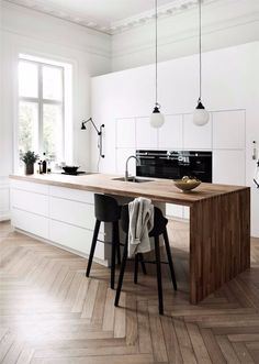 a kitchen with white walls and wooden flooring next to an island in the middle