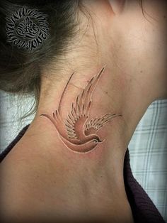 a woman's neck with a bird tattoo on the back of her neck,