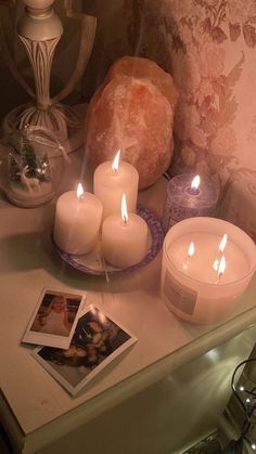 candles and pictures sit on a table with other items