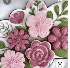 some pink and green decorated cookies on top of a white plate with flowers in the middle