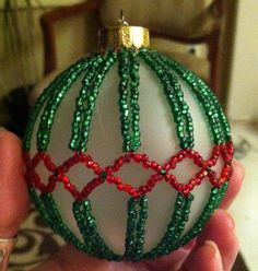 a hand holding a christmas ornament with beads on it