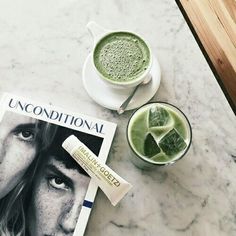 a table topped with two cups of green tea next to an unconditional magazine