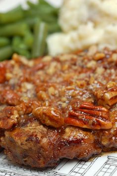 meat with pecans and gravy on it next to green beans