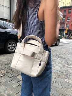 a woman is standing on the street with her purse