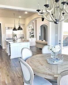 a dining room table with chairs and a chandelier hanging from it's ceiling