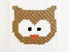 a crocheted square with an owl's face drawn on the front and side